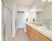 Well-lit bathroom with a large mirror, double sinks, a tiled floor, a glass-enclosed shower, and neutral countertops at 7092 Sw 93Rd Ave # 1, Ocala, FL 34481