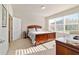 Bedroom with a large window, neutral carpet, wooden furniture, and an ensuite bathroom with plenty of natural light at 7092 Sw 93Rd Ave # 1, Ocala, FL 34481