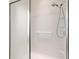 Modern walk-in shower with sleek white tiles, a built-in seat, safety bar, and a convenient handheld showerhead at 7092 Sw 93Rd Ave, Ocala, FL 34481