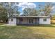 Back of the house with an enclosed patio and a lush green lawn at 7280 Se County Highway 25A, Belleview, FL 34420