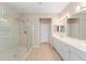 A bright bathroom features an extra-large glass shower, white cabinets, and a double sink at 8961 Se 130Th Loop, Summerfield, FL 34491