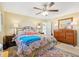 Bright bedroom with a ceiling fan, lamps, and wood furnishings at 9305 Bahia Track Way, Ocala, FL 34472