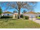 Charming home featuring a manicured lawn, mature tree, and an attached two-car garage at 9305 Bahia Track Way, Ocala, FL 34472