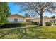 Well-maintained home exterior with lush lawn and landscaping, complemented by a sunny, clear sky at 9305 Bahia Track Way, Ocala, FL 34472