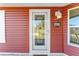 A close-up of the front door with a storm door and a welcome mat saying 