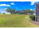 The green lawn is bordered by mature trees with a peek at the screened lanai at 9841 Sw 95Th Loop, Ocala, FL 34481