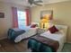Bedroom with two beds, nightstand with table lamp, and a window with curtains at 1118 Pelion Pl, The Villages, FL 32162