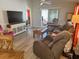 Bright living room featuring stylish furniture, a large TV, and access to the outdoors at 1118 Pelion Pl, The Villages, FL 32162