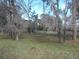 A serene backyard featuring mature trees and lush greenery. The home is visible in the distance at 11665 Sw 72Nd Cir, Ocala, FL 34476