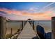 Wooden dock featuring blue stacked chairs, leading out to the water at sunset at 12336 E Highway 25, Ocklawaha, FL 32179