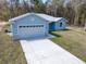 Light blue home with white garage door, stone veneer, and gray roof at 12876 Se 42Nd Ct, Belleview, FL 34420