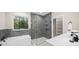 Modern bathroom featuring gray tile, glass shower, soaking tub, white countertop, and ample natural light at 13751 Sw 49Th Pl, Ocala, FL 34481
