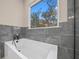 Modern bathtub with gray tile and a large window providing abundant natural light at 13751 Sw 49Th Pl, Ocala, FL 34481