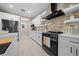 Modern kitchen featuring white cabinets, stainless steel appliances, a stylish backsplash and tile flooring at 13751 Sw 49Th Pl, Ocala, FL 34481