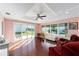 Bright sun room featuring hardwood floors, pink walls, large windows, and a ceiling fan at 2013 Cardona Way, The Villages, FL 32159