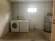 Functional laundry room features washer, dryer, water heater, and overhead shelving for convenient storage at 23 Juniper Pass Ln, Ocala, FL 34480