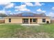View of the home's backyard with a well-maintained lawn, a brick patio, and solar panels on the roof at 234 Locust Pass Loop, Ocala, FL 34472