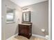 Bathroom features a brown vanity, tiled floors, and a frosted glass window at 234 Locust Pass Loop, Ocala, FL 34472