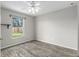 Bedroom features gray flooring, a ceiling fan, and a window overlooking backyard at 234 Locust Pass Loop, Ocala, FL 34472