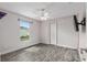Bedroom features gray wood-look flooring, ceiling fan, TV, and a window to outside at 234 Locust Pass Loop, Ocala, FL 34472