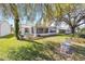 Serene backyard featuring a covered patio, a lush lawn, shaded by mature trees, perfect for outdoor relaxation at 3321 Woodridge Dr, The Villages, FL 32162