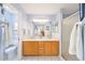 Bright bathroom featuring dual sinks, wood cabinets, a full mirror, and a toilet and shower area at 3321 Woodridge Dr, The Villages, FL 32162