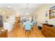 Open dining area with wood floors, modern table, and flowing natural light to the living area with vaulted ceilings at 3321 Woodridge Dr, The Villages, FL 32162