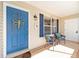Inviting front porch with seating, a bright blue door, and charming decor at 3321 Woodridge Dr, The Villages, FL 32162