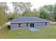 A gray home with a flat backyard and sliding glass doors to a small concrete porch at 3896 Sw 177Th Ter, Dunnellon, FL 34432