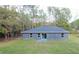 A gray home with a flat backyard and sliding glass doors to a small concrete porch at 3896 Sw 177Th Ter, Dunnellon, FL 34432