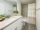 Modern bathroom with gray-veined countertop, a large mirror, a white vanity, and tiled shower with striped curtain at 3896 Sw 177Th Ter, Dunnellon, FL 34432