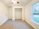 Bright bedroom featuring plush carpet, a ceiling fan, closet and a window with a view of the outdoors at 3896 Sw 177Th Ter, Dunnellon, FL 34432