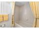Bright bathroom featuring a tub, tile surround, neutral wall color, and matching yellow accents at 5891 Nw 26Th St, Ocala, FL 34482