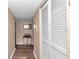 Hallway with beige walls and dark wood floors leading to a closet with louvered doors at 615 Midway Dr # B, Ocala, FL 34472