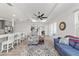 Open-concept living room featuring a blue sofa, patterned chair, view into kitchen, and seamless flow to outdoor spaces at 7908 Sw 89Th Cir, Ocala, FL 34481