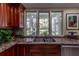 A kitchen sink that features granite countertop, wooden cabinets, and triple casement window at 8380 Se 7Th Avenue Rd, Ocala, FL 34480