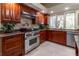 Well-lit kitchen boasts wooden cabinets, granite countertops, stainless steel oven, and tiled backsplash at 8380 Se 7Th Avenue Rd, Ocala, FL 34480