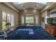 Bright living room boasts large windows with views of the backyard gazebo, vaulted ceiling, and blue carpet at 8380 Se 7Th Avenue Rd, Ocala, FL 34480