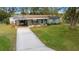 Quaint single-story home with a covered carport, long driveway, and a lush green front yard with mature trees at 8917 Sw 101St Ln, Ocala, FL 34481