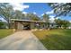 Charming single-story home with a carport, well-maintained lawn, and a long driveway, set under a blue sky with scattered clouds at 8917 Sw 101St Ln, Ocala, FL 34481