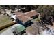Aerial view of a quaint home with a large deck, a green metal carport, and a neatly manicured lawn surrounded by lush greenery at 10370 Sw 110Th St, Dunnellon, FL 34432