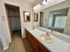 Well-lit bathroom features dual sinks, updated vanity, large mirror, and walk-in closet access at 10370 Sw 110Th St, Dunnellon, FL 34432