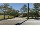 Rural property featuring a long driveway, a green lawn, and a backdrop of mature trees against a clear blue sky at 10370 Sw 110Th St, Dunnellon, FL 34432