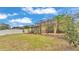 View of a screened-in lanai extending from the back of the house, overlooking a grassy yard and white fence at 1073 Vinsetta Cir, Winter Garden, FL 34787