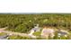 Aerial view of a gray single-Gathering home with a spacious lawn surrounded by lush trees in a peaceful neighborhood at 114 Bay Dr, Ocklawaha, FL 32179