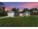 Charming gray single-Gathering home featuring a blue front door, a two-car garage, and a well-maintained lawn at sunset at 114 Bay Dr, Ocklawaha, FL 32179