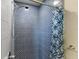A modern shower with glass tiles and blue patterned curtain at 12424 Sw 140Th Loop, Dunnellon, FL 34432