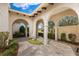 Arched courtyard with stone tiled floor, featuring lush landscaping and ornamental garden art at 12424 Sw 140Th Loop, Dunnellon, FL 34432