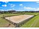 Aerial shot of an equestrian arena with fencing and a ranch house, surrounded by beautiful green fields and trees at 12424 Sw 140Th Loop, Dunnellon, FL 34432