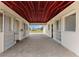 Interior view of a horse barn with stalls, a red ceiling, and a brick-paved walkway, offering a functional design at 12424 Sw 140Th Loop, Dunnellon, FL 34432